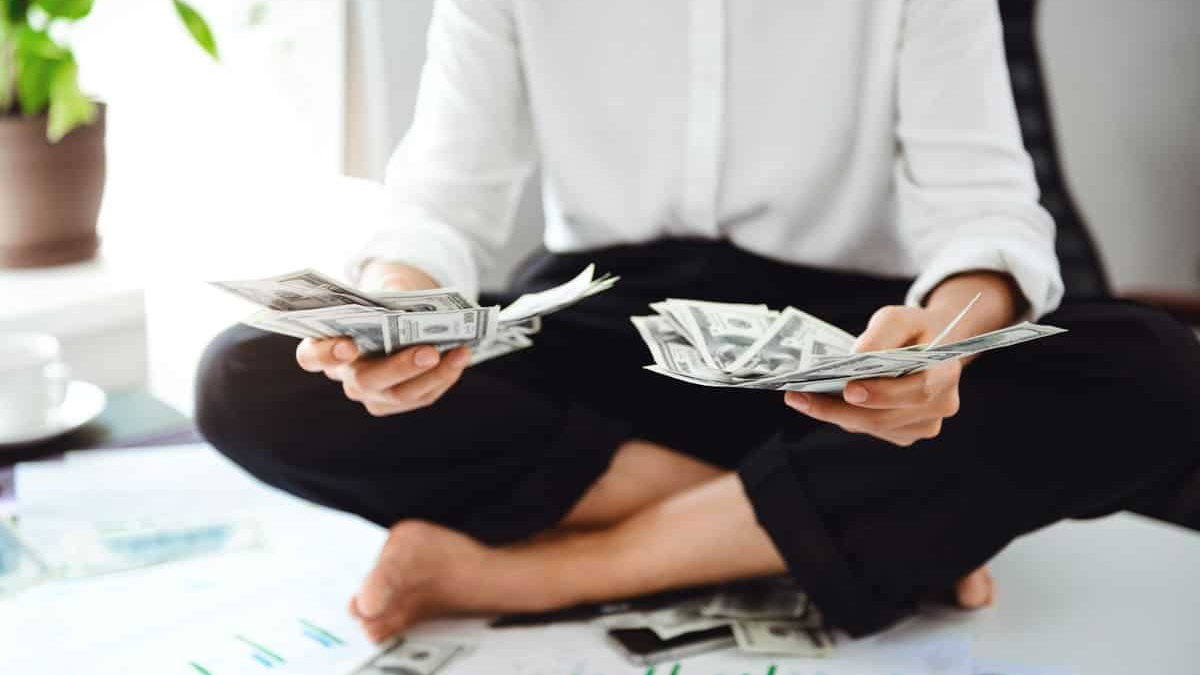 Investimentos e gestão financeira representados por uma pessoa sentada de pernas cruzadas sobre uma mesa repleta de gráficos e planilhas.