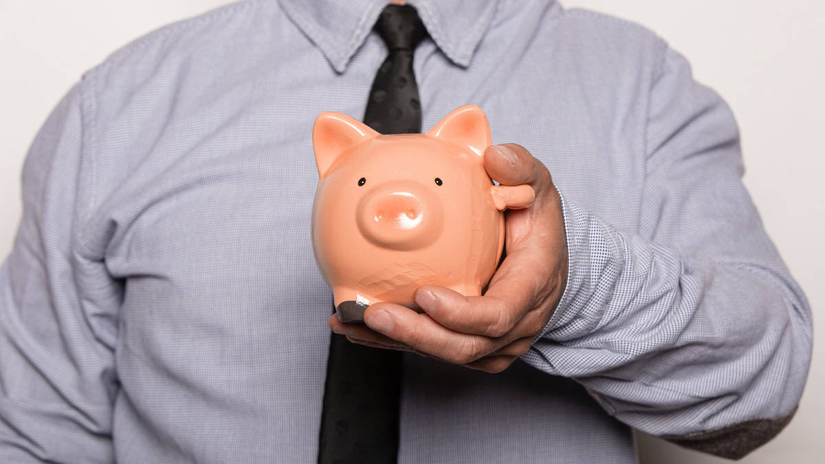 Investir com segurança: homem segurando cofrinho que representa proteção e estabilidade financeira