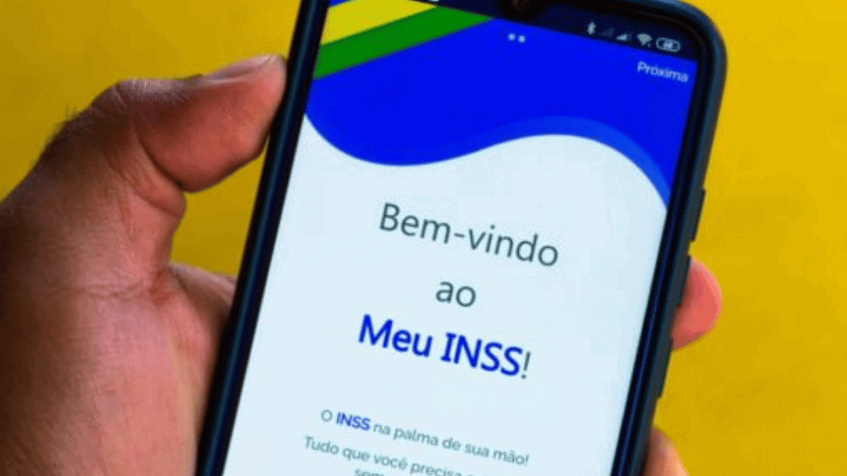Mão segurando um smartphone exibindo o app do INSS, simbolizando o canal de atendimento do INSS e a modernização dos serviços digitais para beneficiários.