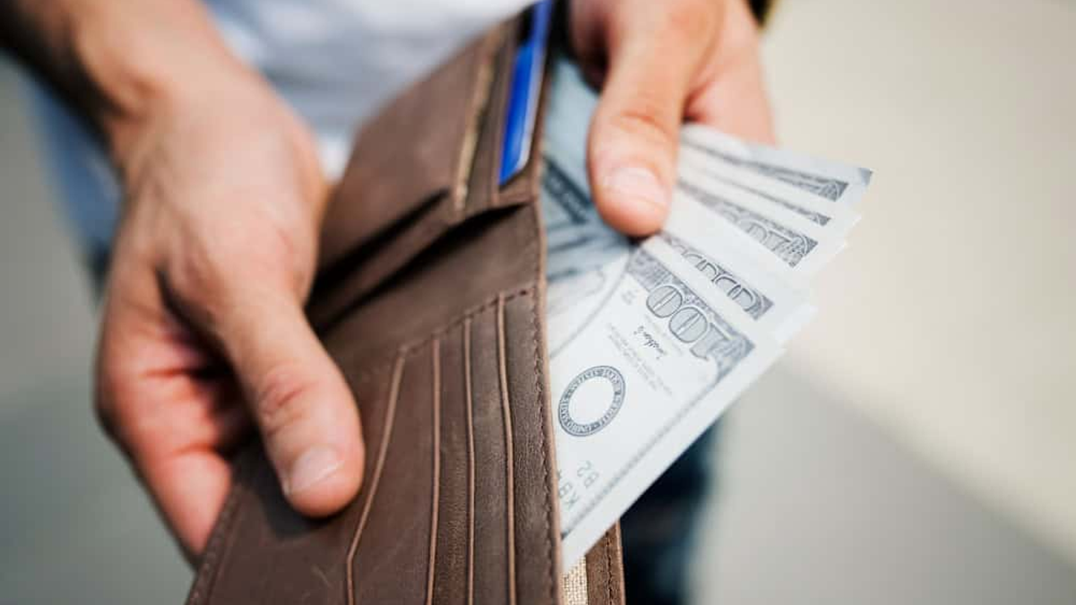 Imagem de uma carteira cheia de dinheiro, ilustrando o conceito de liberdade financeira e a importância de planejar o orçamento para gerenciar dívidas e alcançar estabilidade econômica.