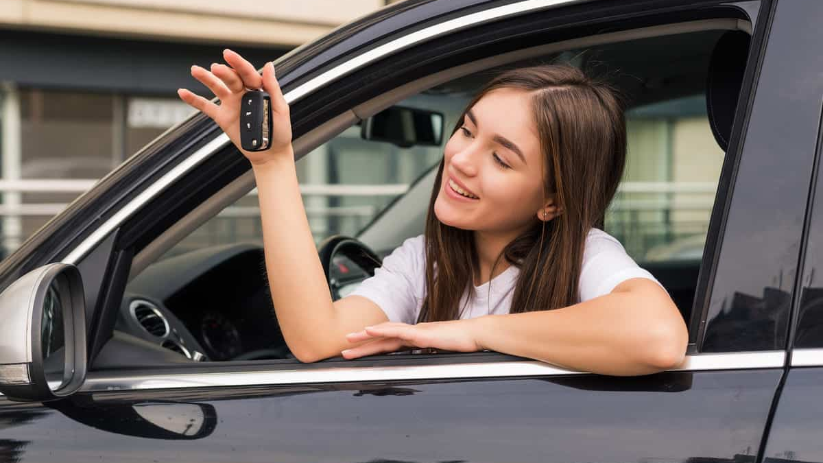 emprestimo pessoal para compra de carro, mulher sorrindo dentro do veículo com a chave na mão, simbolizando conquista e aprovação de crédito