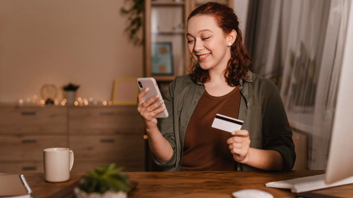 Imagem ilustrativa de uma mulher sorridente usando um notebook na cozinha, representando a praticidade e a segurança do empréstimo Santander UseCasa. A cena transmite a facilidade da contratação digital e o controle financeiro proporcionado pelo crédito com garantia de imóvel.