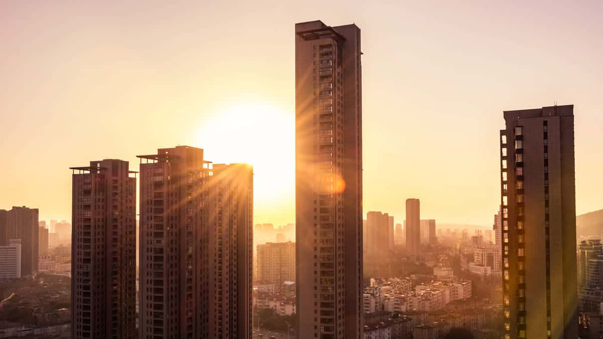 Vista urbana ao pôr do sol com edifícios altos iluminados pela luz solar — conceito de investimento em fundos imobiliários
